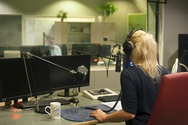 Blonde woman at radio station talks into microphone