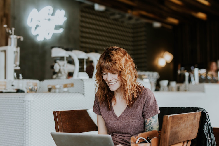 red haired woman sits at laptop