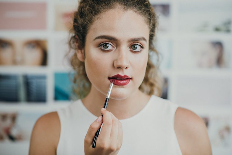 Female beauty blogger applies red lipstick