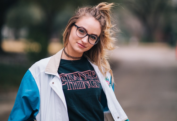 A smiling girl in glasses wears a Stranger Things T shirt 