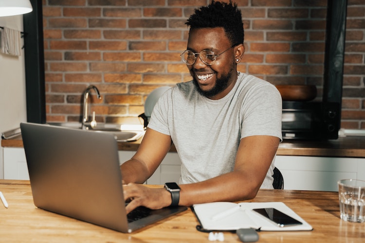 Black man smiling at laptop