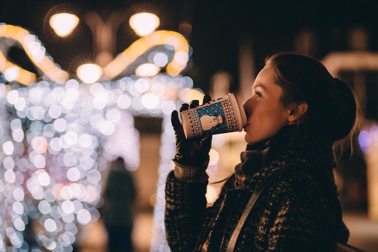 Girl drinks from coffee cup at German market