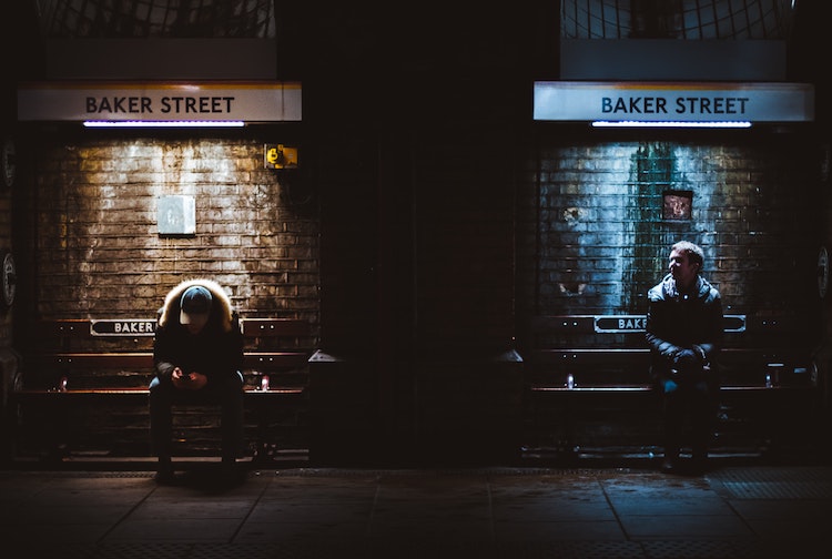 Two men on benches at dark Baker Street station 