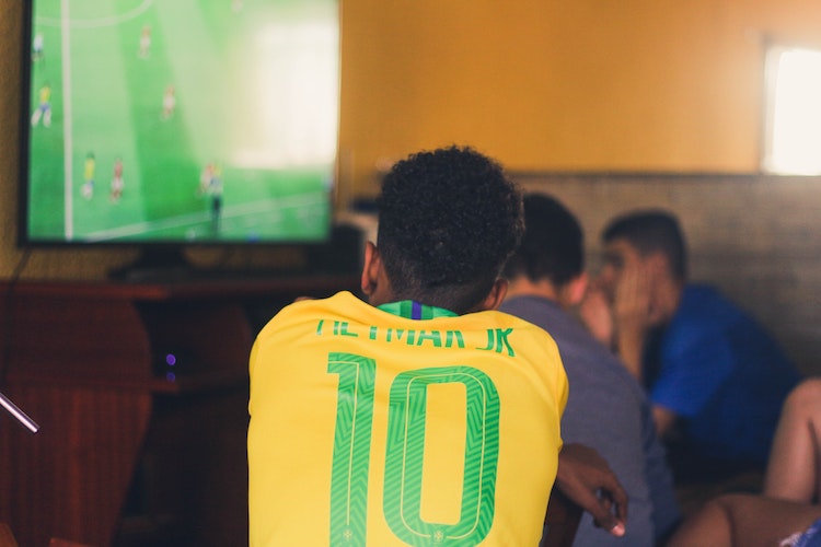 Brazilian football fan in jersey watching TV