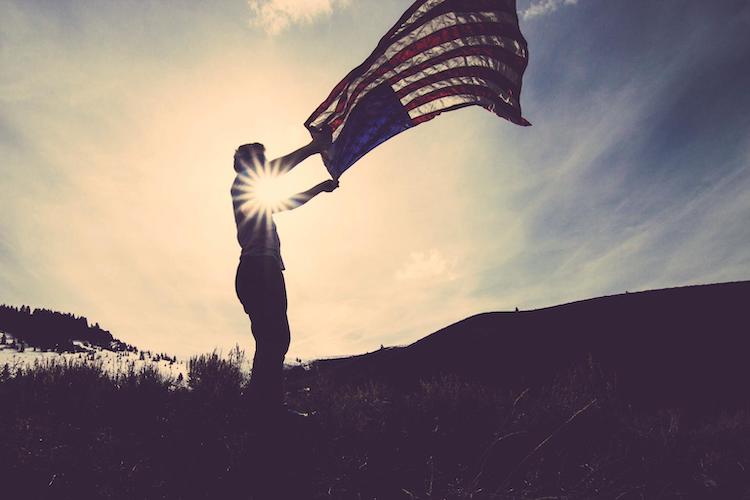 Man waving USA flag at sunrise