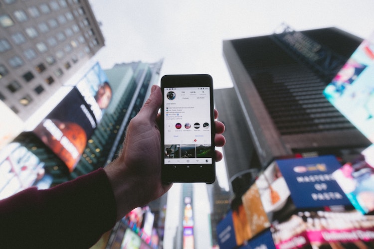 mobile phone screen on instagram in front of city buildings