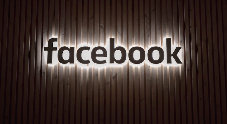 Facebook logo illuminated on wood background 