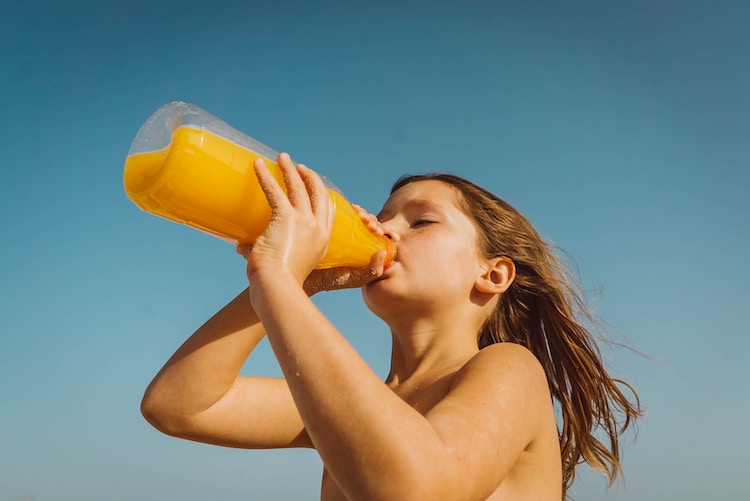 Girl drinks orange juice from bottle